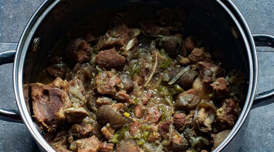 Braised meat with onions and spices in a large cooking pot.