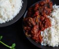 Nigerian tomato stew with goat meat served on a plate with white rice.