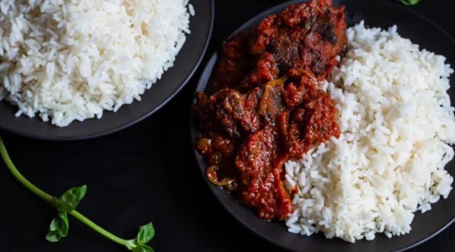 Nigerian tomato stew with goat meat served on a plate with white rice.