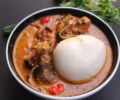 Peanut soup served in a bowl with assorted meats and pounded yam.