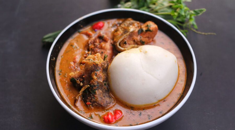 Peanut soup served in a bowl with assorted meats and pounded yam.