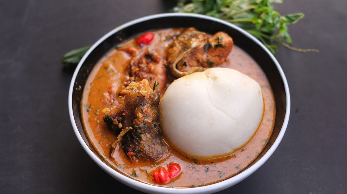 Peanut soup served in a bowl with assorted meats and pounded yam.