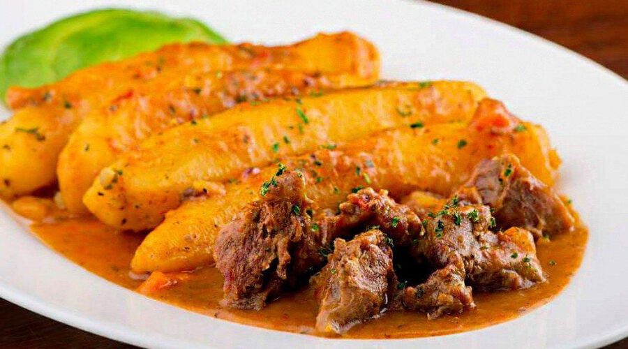 Matoke with meat served on a white plate