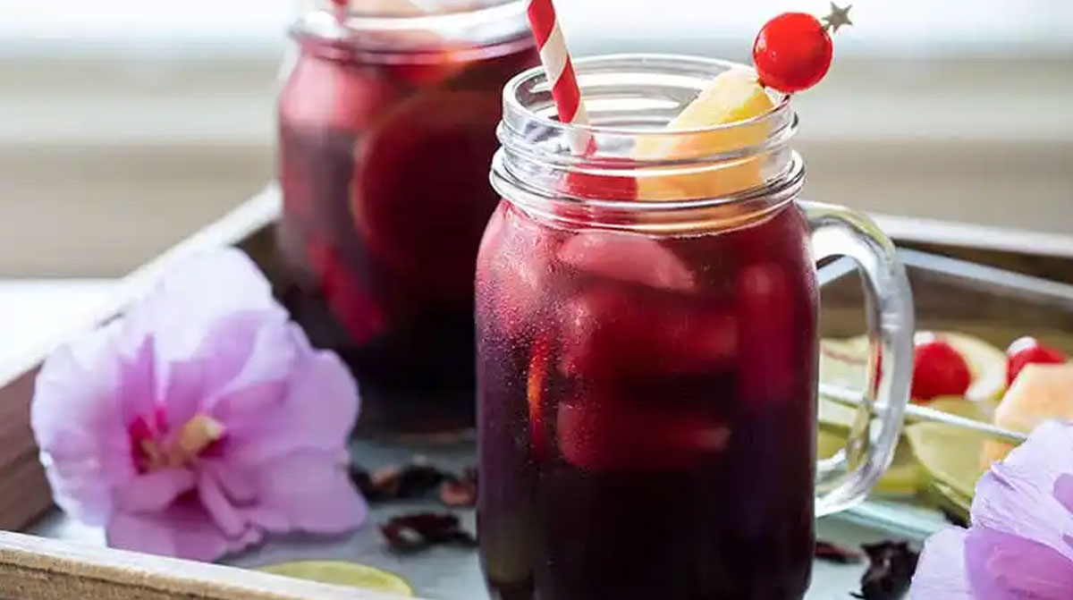 Nigerian zobo drinks on a tray with hibiscus flowers.