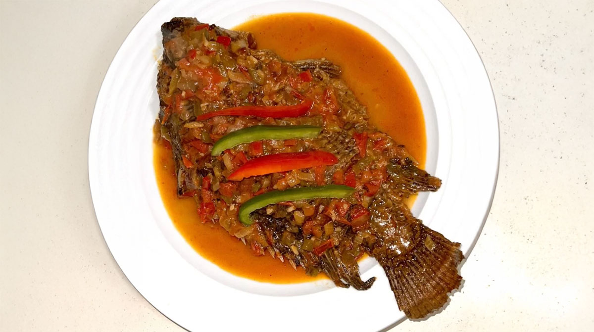Kenyan style whole fried tilapia stew served on a plate