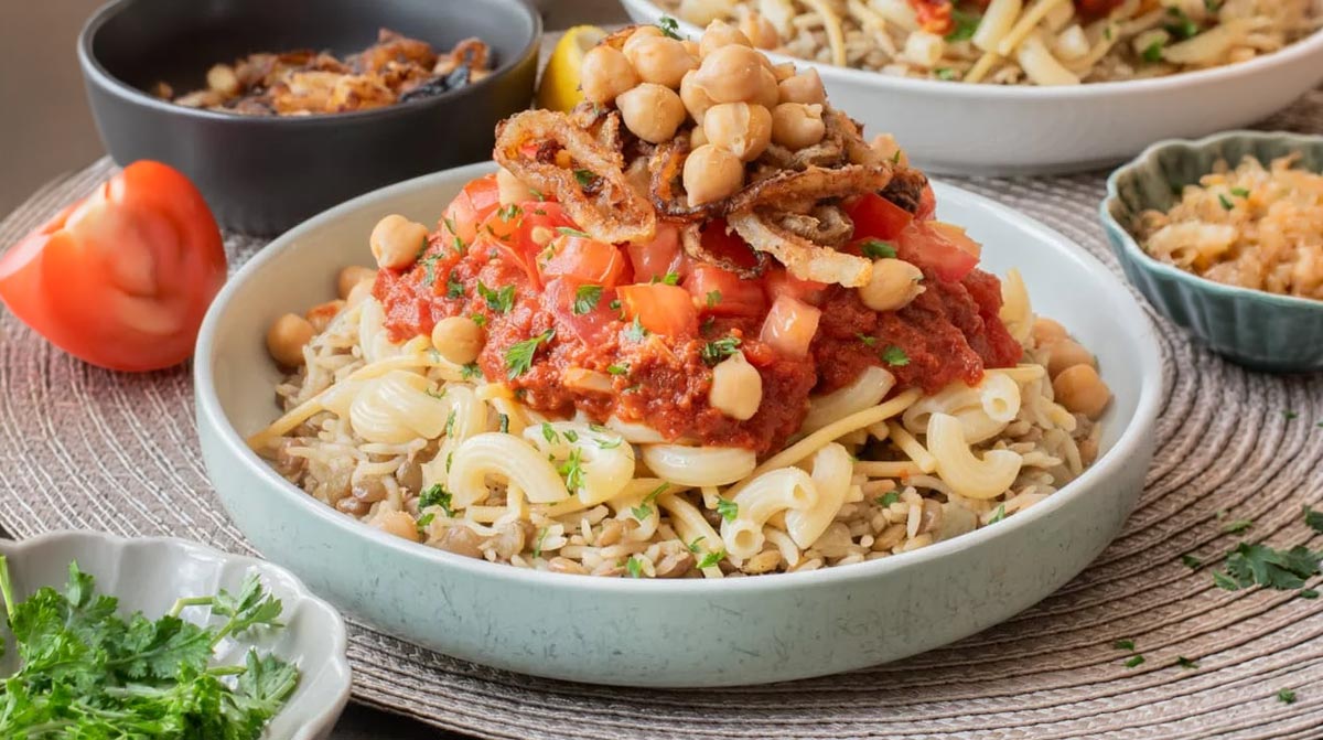 Egyptian Koshari with rice, lentils, pasta, chickpeas, spiced tomato sauce, and crisp onions