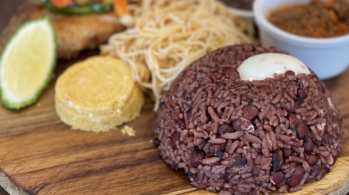 Ghanaian waakye rice and beans served with a boiled egg, gari and accompaniments